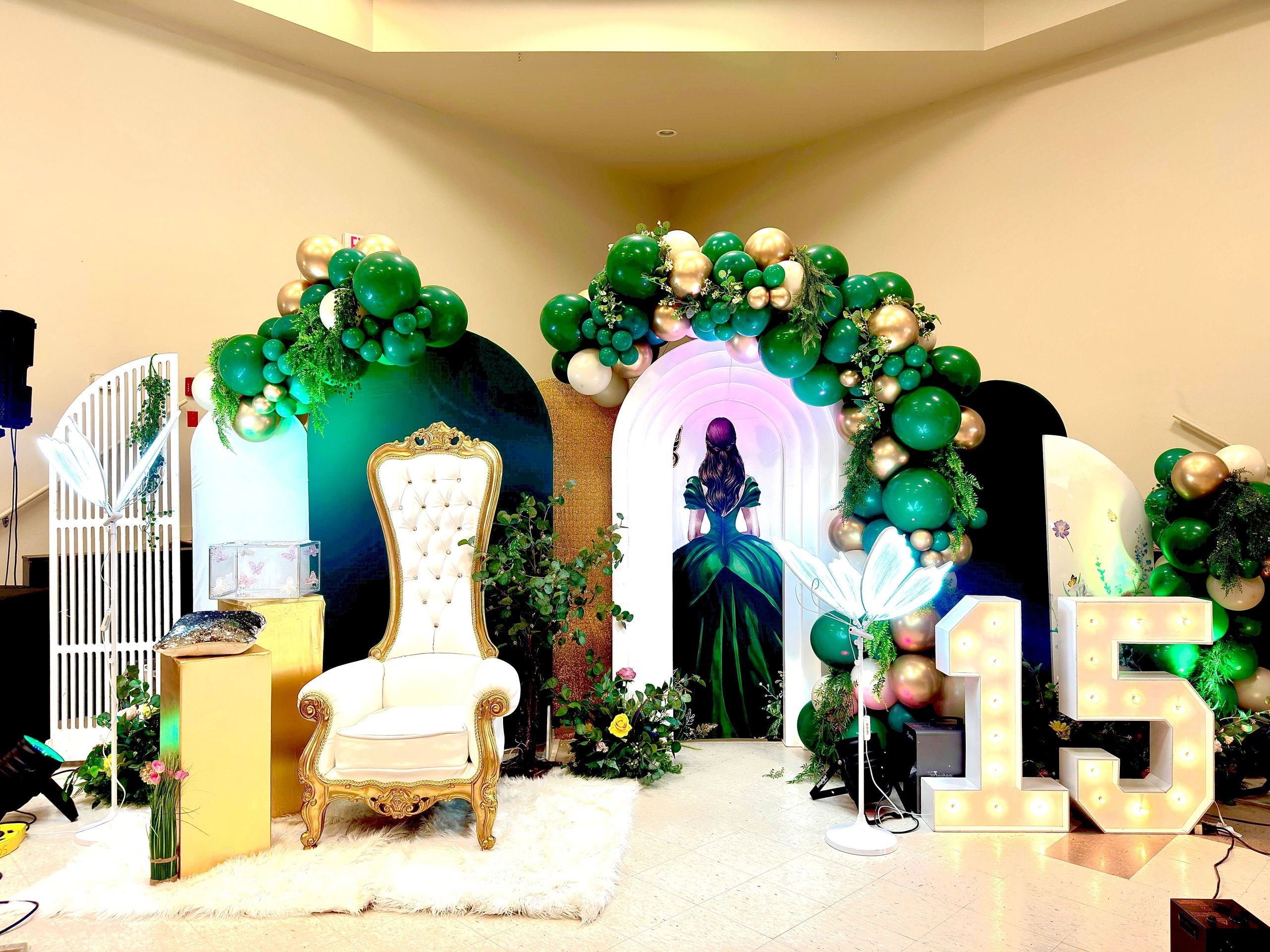 Luxury quinceañera event décor in Calgary featuring an emerald green and gold balloon garland, custo