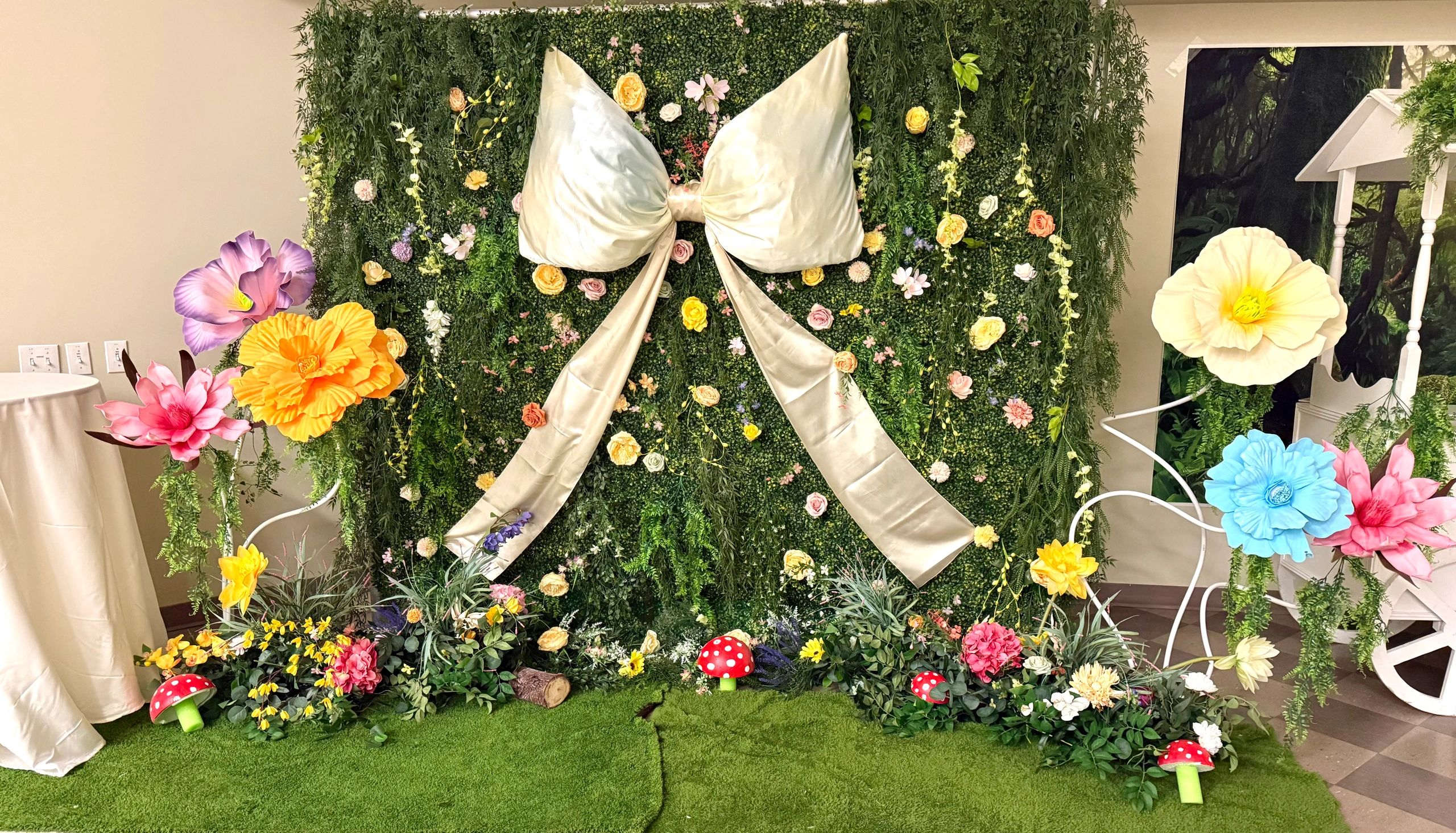 Premium enchanted garden event décor in Calgary featuring a lush greenery wall backdrop, oversized b