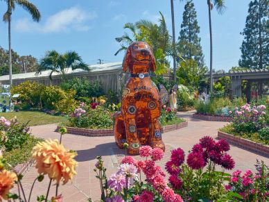 Brown dog statue made of bottle caps in garden.