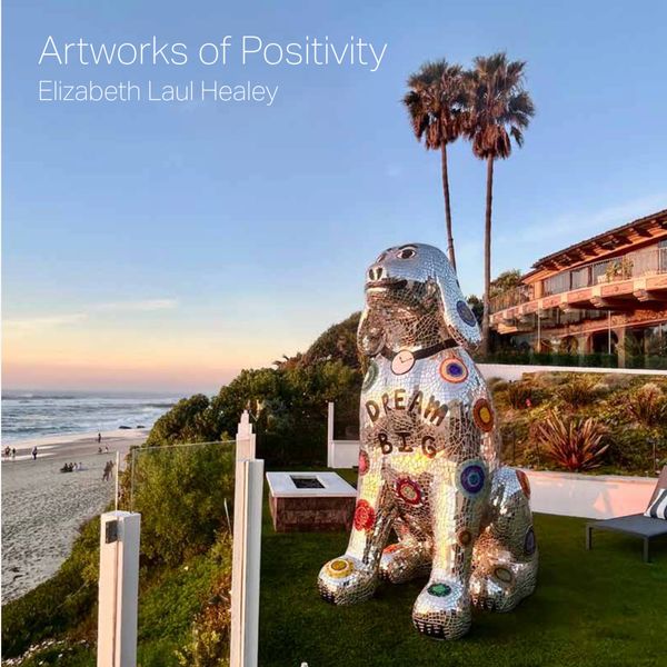 Mosaic dog sculpture with positive message on beach.