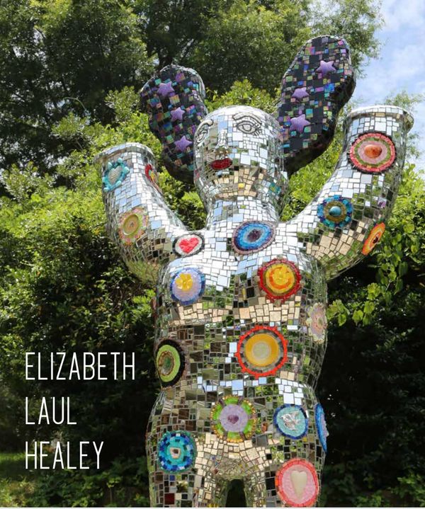 Colorful mosaic sculpture with raised arms outdoors.