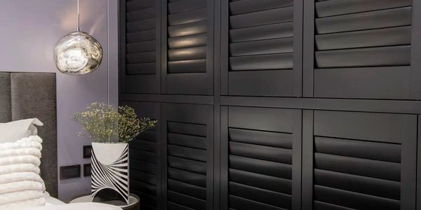 Modern bedroom with custom wooden shutters that are black. 