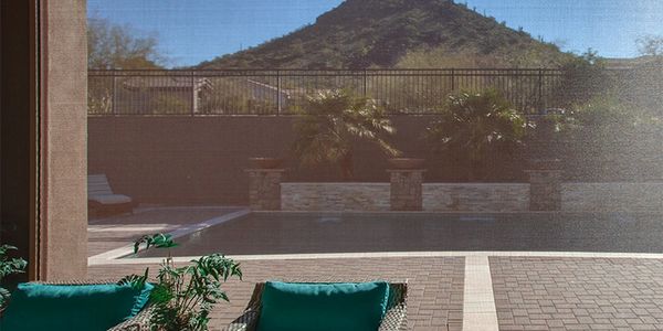 Outdoor track motorized shade beside a pool near the mountains. 