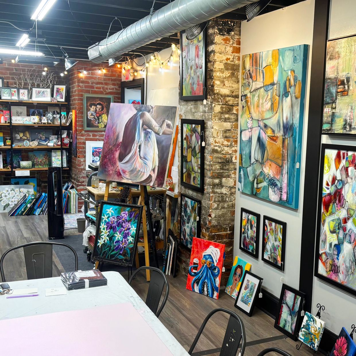 Art gallery with diverse paintings and exposed brick walls.
