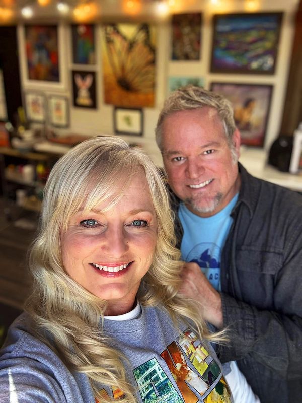 Smiling couple posing for a selfie in a colorful, art-filled room.