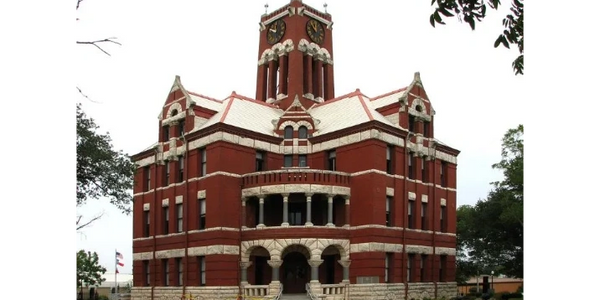 Historic red brick courthouse with a clock tower and arched entrance.