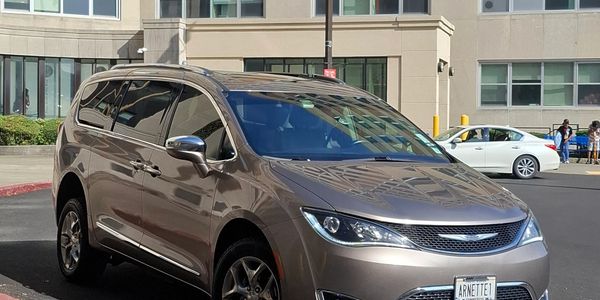 Silver Chrysler minivan parked outside a building.