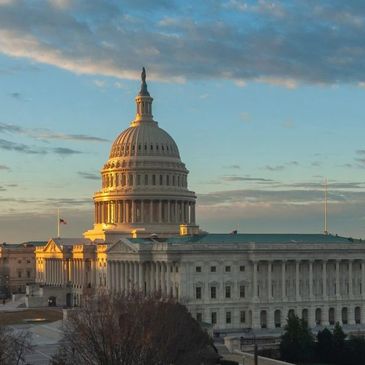 The U.S. Capitol building illuminated by the setting sun under a partly cloudy sky.