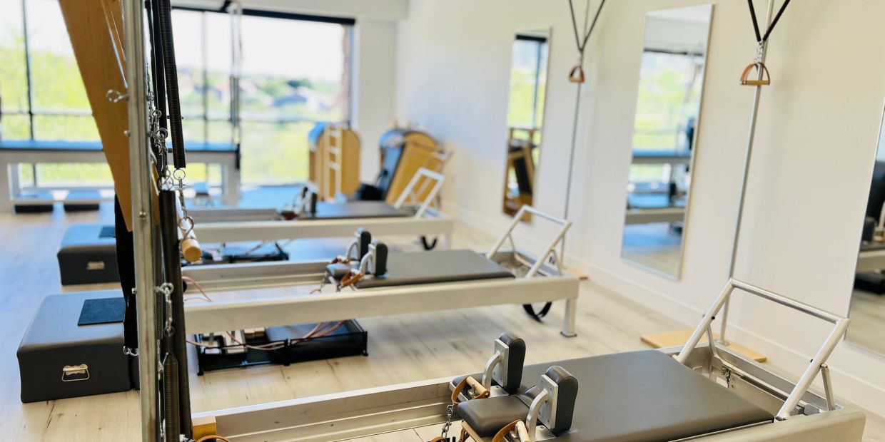 Modern Pilates reformer machines lined up in a bright, spacious studio.