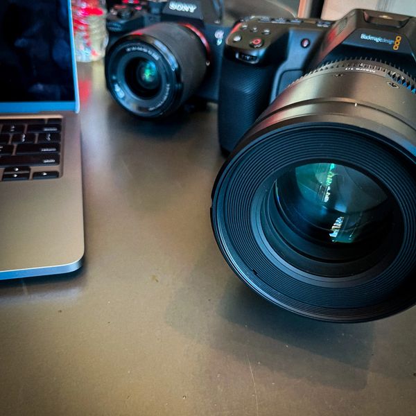 Close-up of professional camera lenses and a laptop keyboard on a desk.
