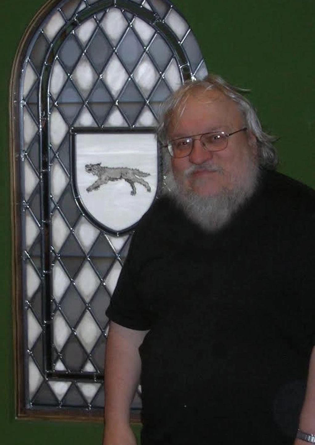 a man standing in front of a stained glass window depicting a dire wolf