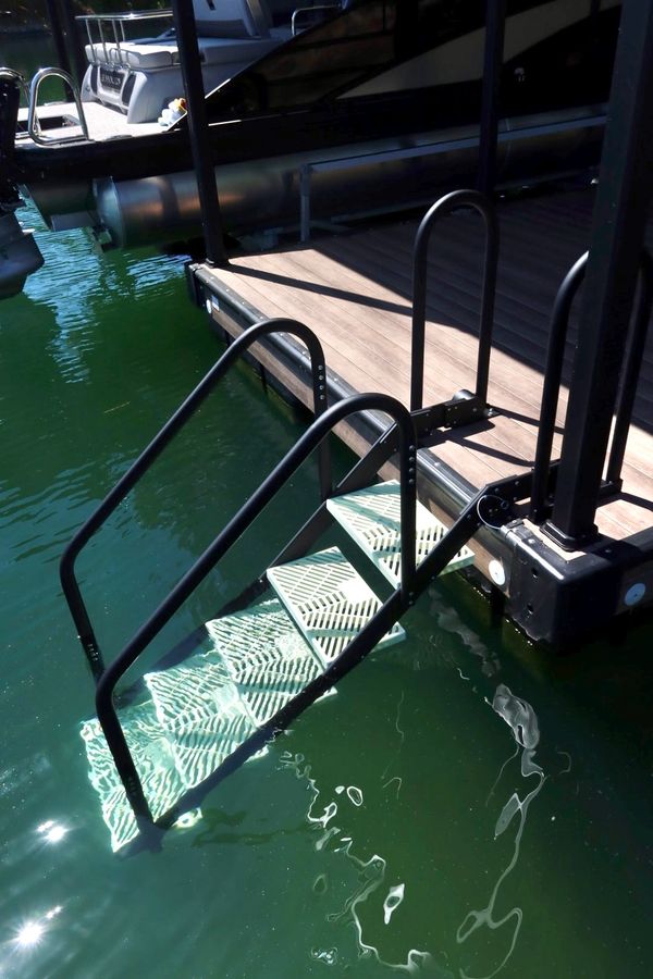 A dock ladder partially submerged in water with a wooden dock and boat nearby.