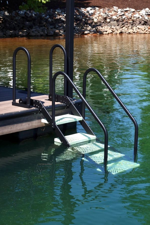 Metal stairs leading from a dock into clear water.