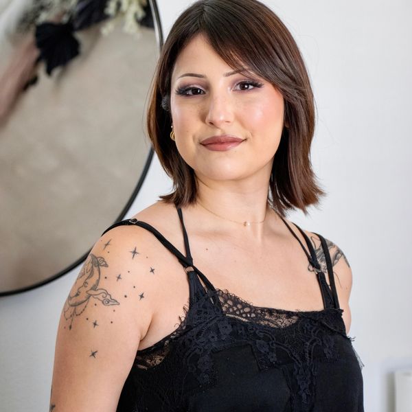 Young woman with tattoos posing confidently in black lace top.