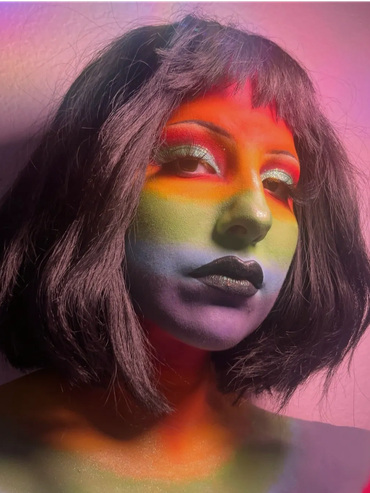Person with rainbow-colored face paint and black lipstick.