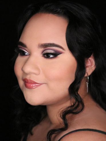 Close-up portrait of a woman with elegant makeup and curled hair.