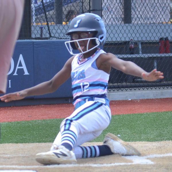 Young baseball player sliding into home plate during a game.