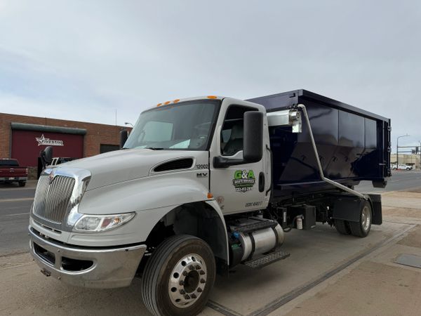 White and blue waste management truck parked on a city street.
