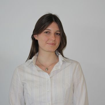 Young woman with brown hair in a white shirt.