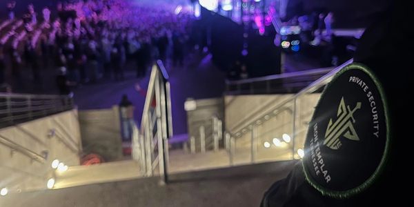 Security personnel at a crowded event with purple lighting.