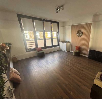 A minimally furnished room with large windows and wooden floors.