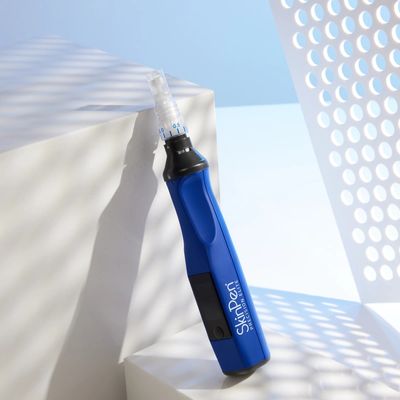 Blue SkinPen microneedling device placed on a white surface with artistic shadows.