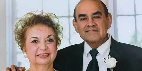 Elderly couple proudly holding their wedding photo from years ago.