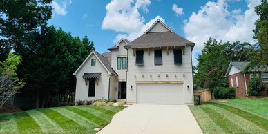 A modern two-story house with a gray exterior, gabled roofs, and clean-cut landscaping under a cloud