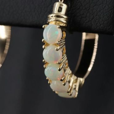 Close-up of a gold earring with iridescent opal stones.