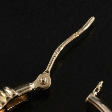 Close-up of a gold watch hand on a black background.