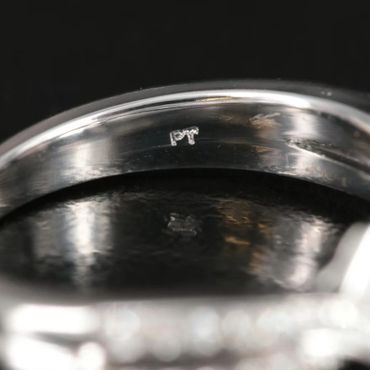 Close-up of a silver ring with a hallmark stamp inside.