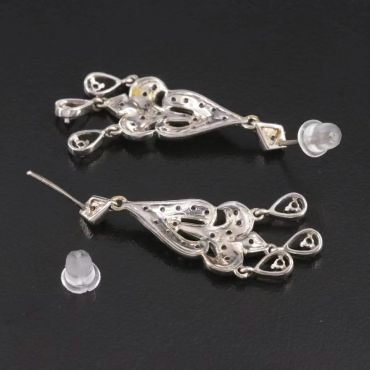 Pair of intricate silver earrings with clear backs.