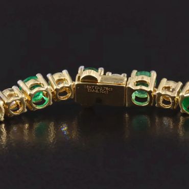 Close-up of a gold and emerald bracelet clasp.