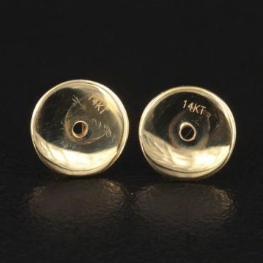 Close-up of two 14KT gold earring backs.