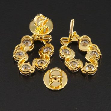 Gold earrings with embedded stones on a black surface.