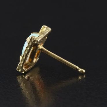 Close-up of a gold and blue stud earring.