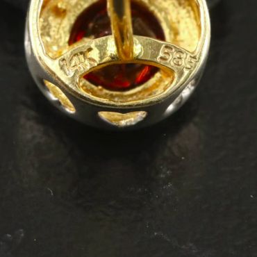 Close-up of a gold ring with red gemstone and markings.