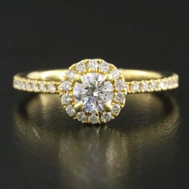 Elegant gold ring with central diamond and diamond halo.