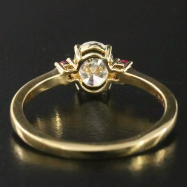 Gold ring with a central diamond and two smaller red stones.