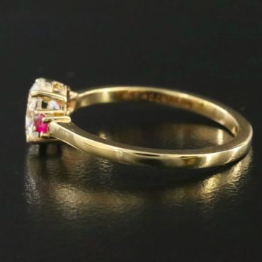 Gold ring with diamonds and a small red stone.