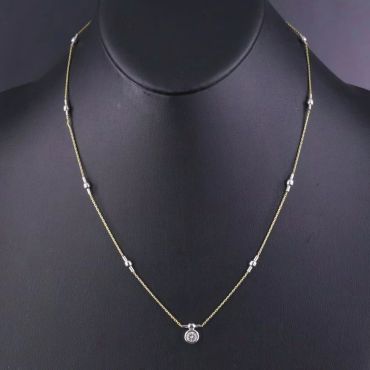 Delicate gold chain necklace with a small round pendant.
