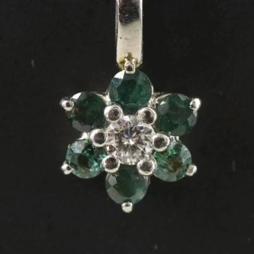 Flower-shaped pendant with green and clear stones.