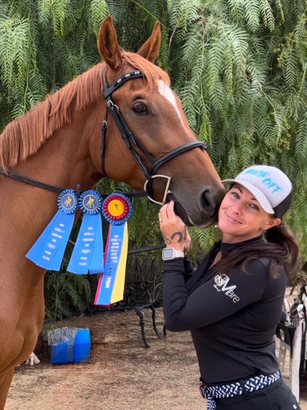 Woman with her horse adorned with blue and red award ribbons.