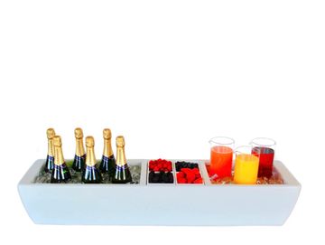 Rectangular cooler holding champagne, berries, and juice glasses.