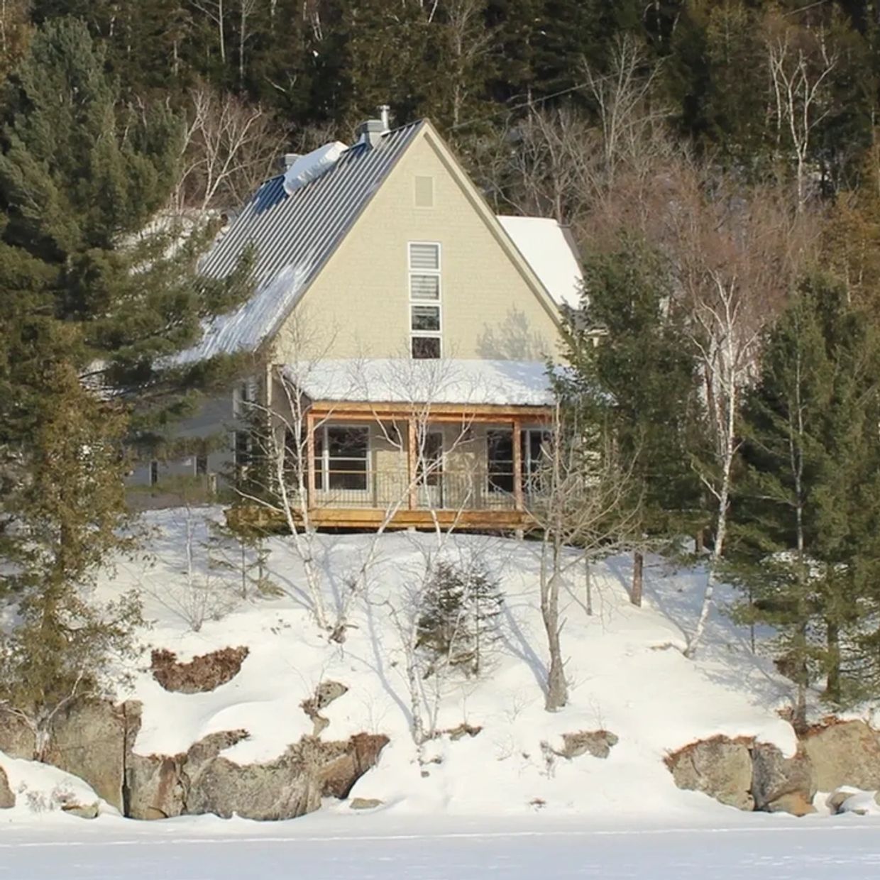Maison en bois entourée de neige et d'arbres.