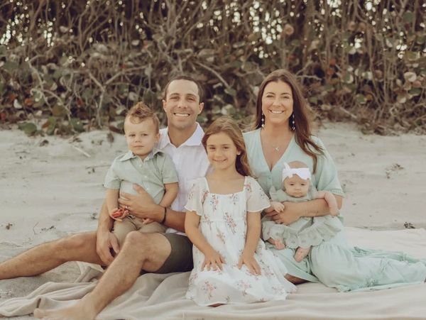 A happy family of five posing on a beach with neutral tones and soft smiles.