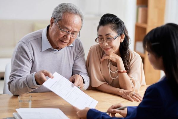 Concentrated senior man and his pretty wife studying terms of real estate purchase agreement