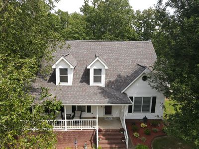 A charming white house with a front porch surrounded by greenery.