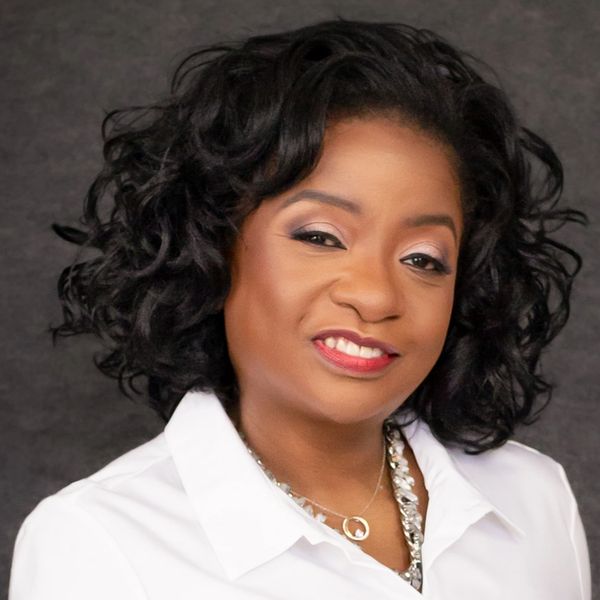 Confident woman with curly hair smiling, dressed in white.
