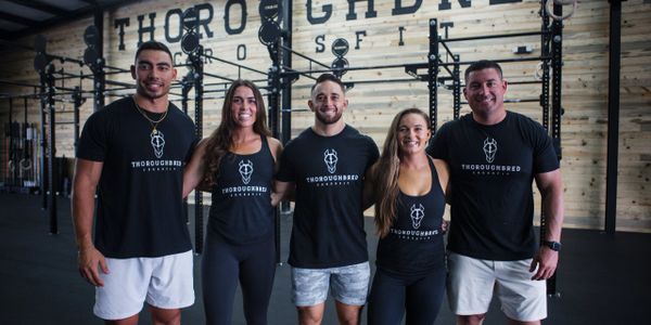 Five people wearing Thoroughbred CrossFit shirts posing in a gym.